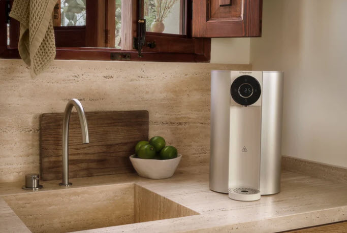 Countertop SMR Water Purifier placed on a natural stone countertop beside a kitchen sink and bowl of limes.