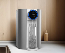 Countertop SMR Water Purifier dispensing filtered water into a clear bottle on a kitchen counter.